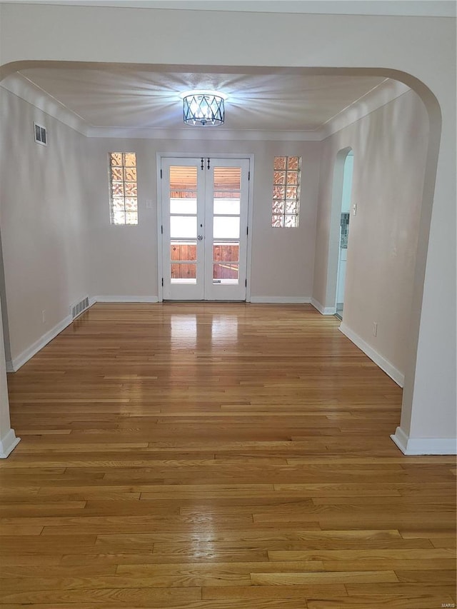 unfurnished room with crown molding, light hardwood / wood-style floors, and french doors