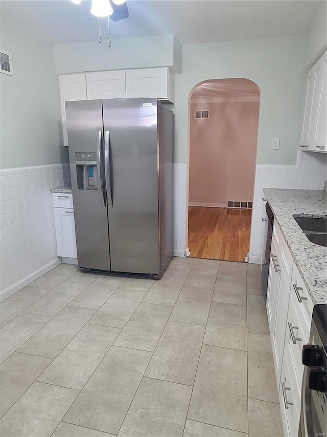 kitchen with light tile patterned flooring, sink, white cabinets, light stone counters, and stainless steel appliances