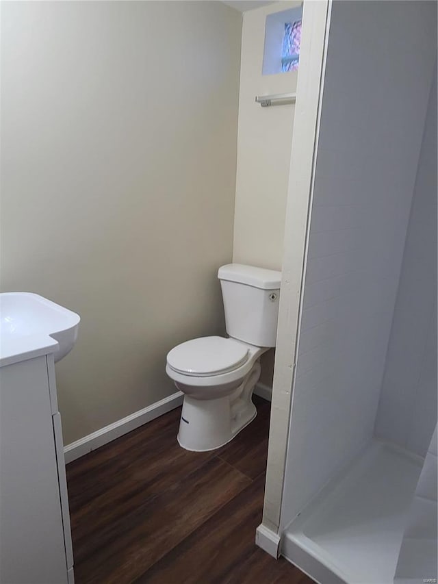 bathroom with hardwood / wood-style flooring, vanity, a shower, and toilet