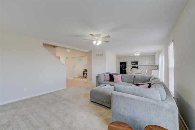 carpeted living room featuring sink and ceiling fan