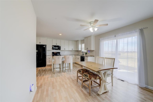 dining room featuring sink, ceiling fan, and light hardwood / wood-style flooring