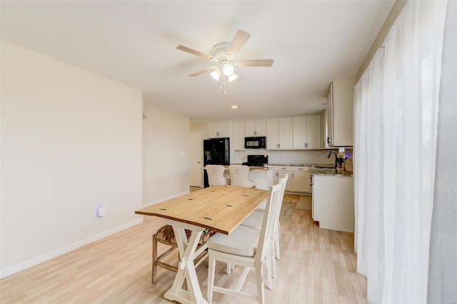 dining space featuring sink, light hardwood / wood-style flooring, and ceiling fan