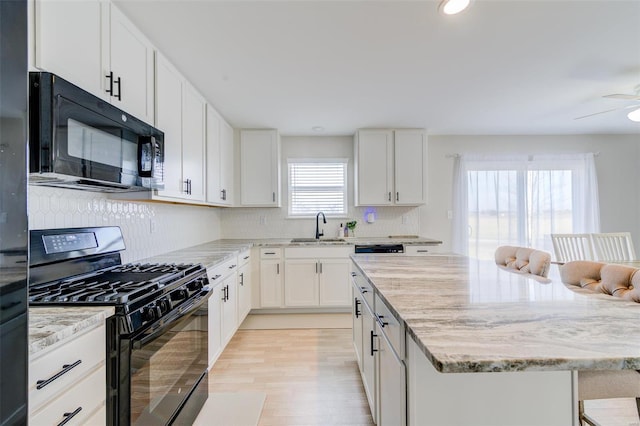 kitchen featuring white cabinetry, sink, decorative backsplash, black appliances, and light stone countertops