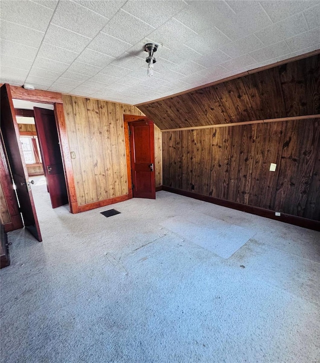 additional living space featuring lofted ceiling and wood walls