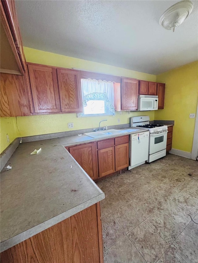 kitchen with sink, white appliances, and a textured ceiling