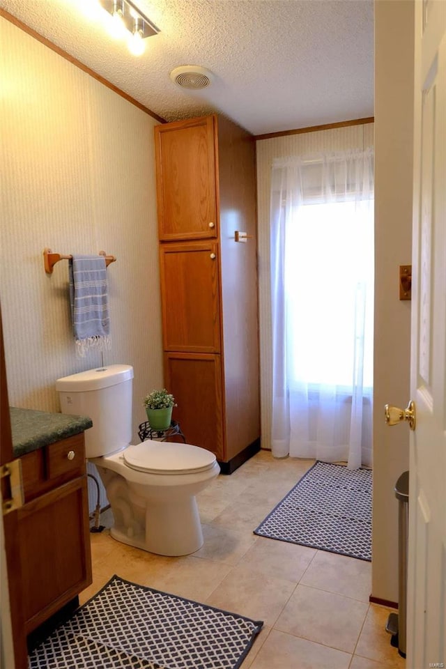 half bathroom featuring a textured ceiling, visible vents, plenty of natural light, and toilet