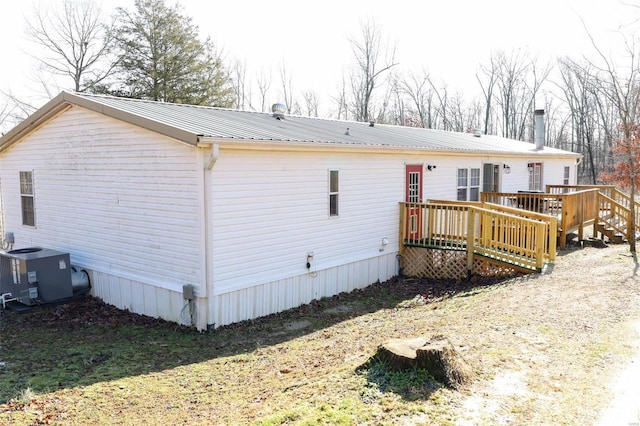 rear view of property featuring metal roof, a deck, and cooling unit