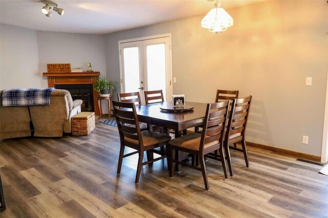 dining room with a fireplace, wood finished floors, visible vents, baseboards, and french doors