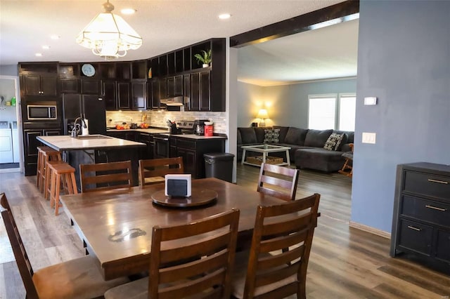 dining area with washing machine and dryer, recessed lighting, wood finished floors, beamed ceiling, and an inviting chandelier