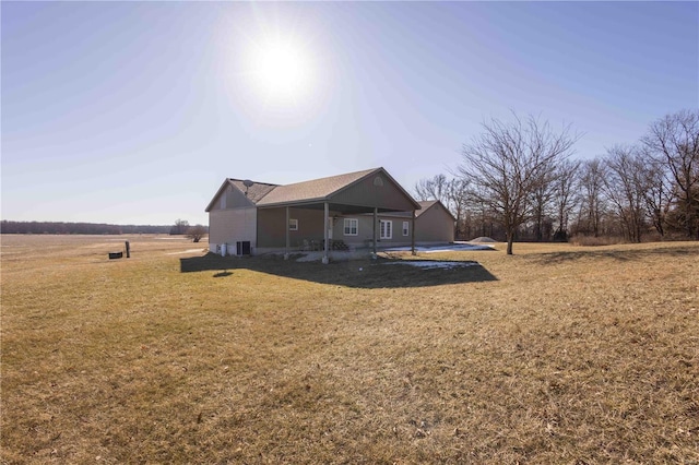 rear view of house with a yard, central air condition unit, and a rural view