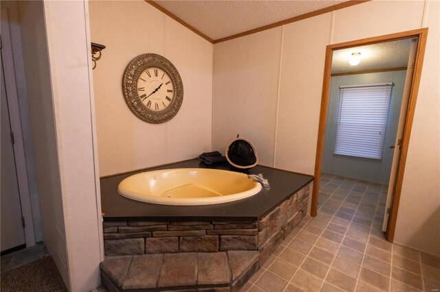 bathroom with ornamental molding, lofted ceiling, a relaxing tiled tub, and a textured ceiling