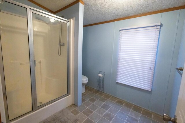 bathroom featuring toilet, a shower with shower door, a textured ceiling, ornamental molding, and tile patterned flooring