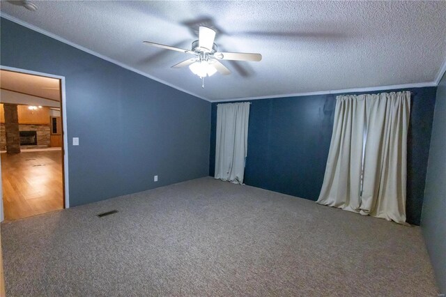 unfurnished bedroom featuring vaulted ceiling, a textured ceiling, ornamental molding, carpet flooring, and ceiling fan