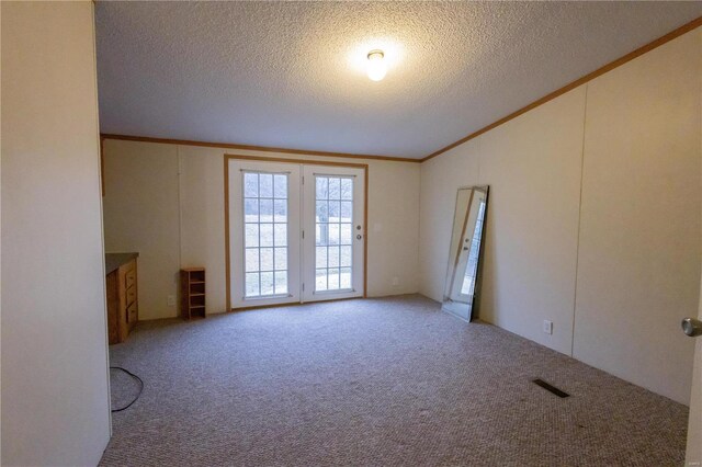 spare room with crown molding, lofted ceiling, carpet floors, and a textured ceiling