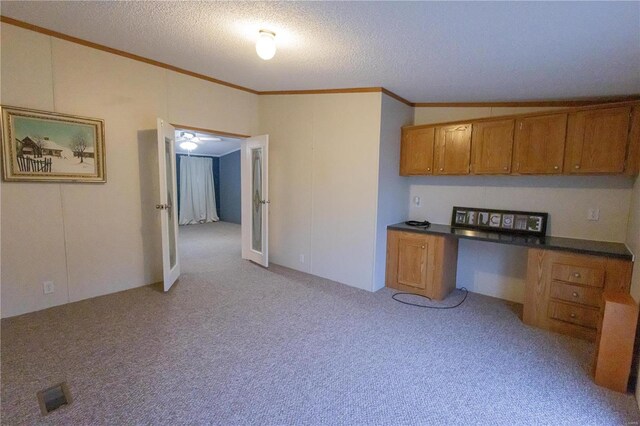 kitchen featuring light carpet, built in desk, ornamental molding, and a textured ceiling