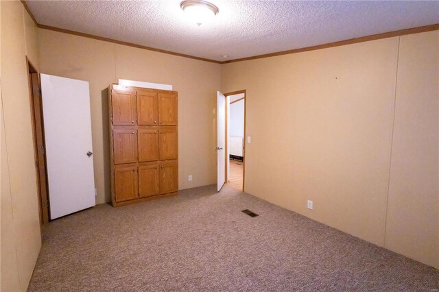 unfurnished bedroom featuring light colored carpet, ornamental molding, and a textured ceiling