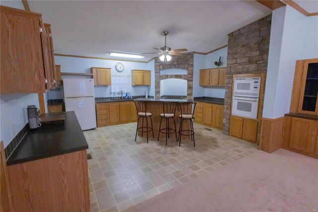 kitchen with white appliances, a breakfast bar, ornamental molding, a kitchen island, and vaulted ceiling