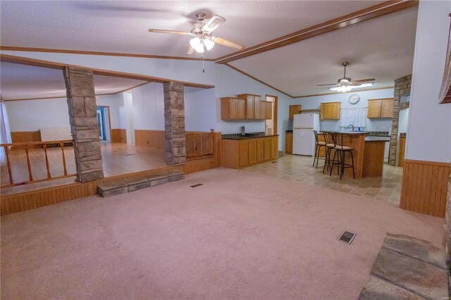 unfurnished living room featuring light carpet, ornamental molding, decorative columns, and lofted ceiling