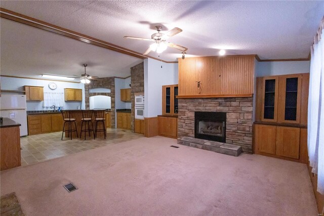 unfurnished living room featuring lofted ceiling, a fireplace, light colored carpet, and a textured ceiling