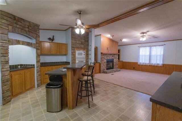 kitchen with crown molding, ceiling fan, wooden walls, and a kitchen island