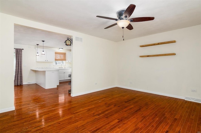 unfurnished living room featuring dark wood-type flooring and ceiling fan