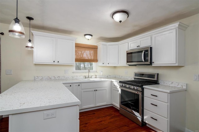 kitchen featuring appliances with stainless steel finishes, pendant lighting, white cabinetry, sink, and kitchen peninsula