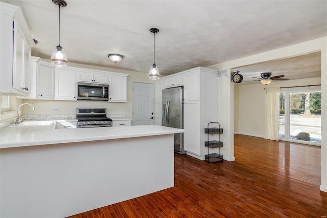 kitchen with white cabinetry, appliances with stainless steel finishes, pendant lighting, and kitchen peninsula