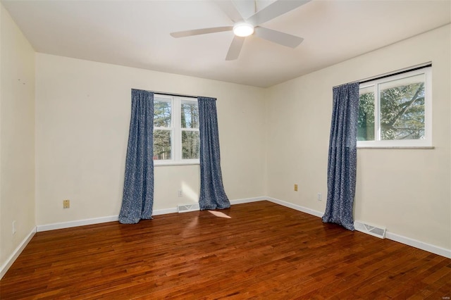 empty room with dark wood-type flooring, a wealth of natural light, and ceiling fan