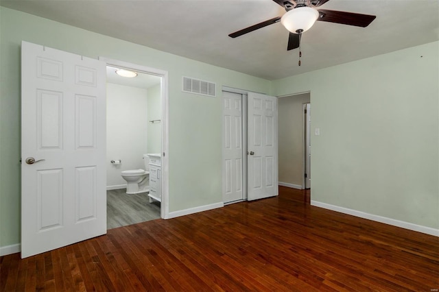 unfurnished bedroom featuring ceiling fan, dark hardwood / wood-style floors, a closet, and ensuite bath