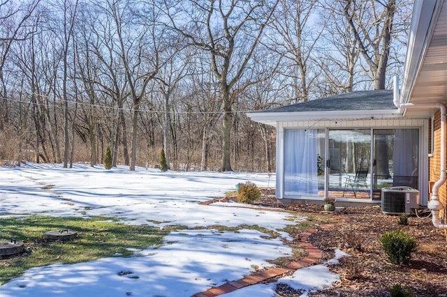 snowy yard with a sunroom and cooling unit