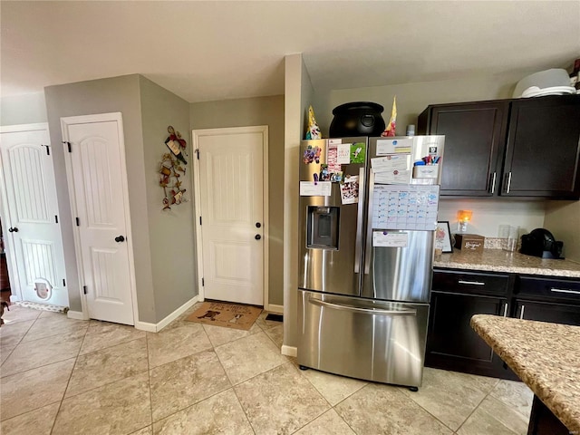 kitchen featuring light stone counters, stainless steel fridge, and light tile patterned flooring