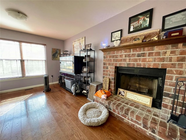 living room featuring a brick fireplace and wood-type flooring