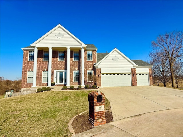 greek revival inspired property with a garage, brick siding, concrete driveway, and a front yard