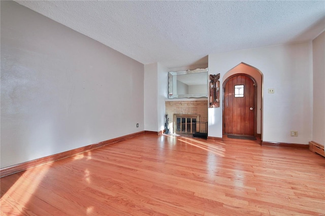 unfurnished living room with light hardwood / wood-style flooring and a textured ceiling