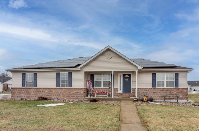 single story home with a porch, a front yard, and solar panels