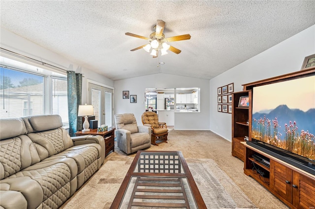 living room featuring vaulted ceiling, light colored carpet, ceiling fan, and a textured ceiling