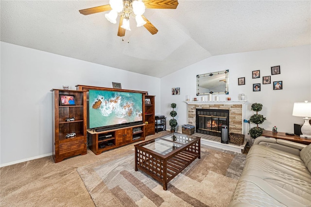 living room featuring lofted ceiling, ceiling fan, carpet flooring, a textured ceiling, and a stone fireplace