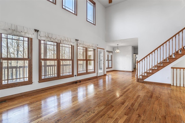 unfurnished living room with hardwood / wood-style flooring and a towering ceiling