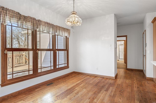 unfurnished room with a notable chandelier and light hardwood / wood-style flooring