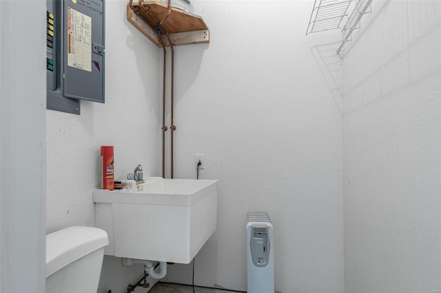 bathroom with sink, electric panel, and toilet