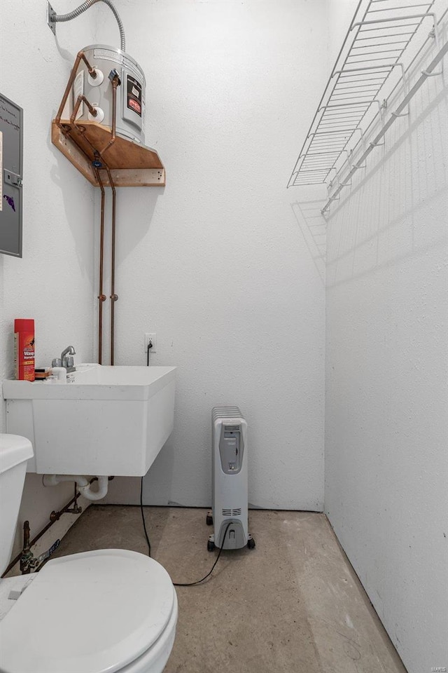 bathroom with toilet, concrete flooring, and sink