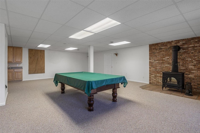 game room featuring a wood stove, light carpet, and a drop ceiling