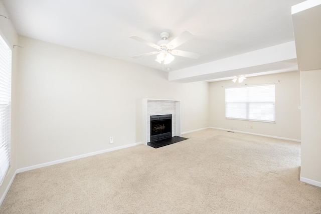 unfurnished living room with carpet, a fireplace with flush hearth, baseboards, and a ceiling fan