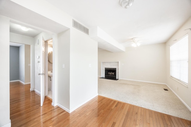 interior space featuring light wood-style floors, visible vents, baseboards, and a premium fireplace