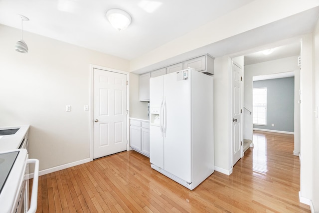 kitchen with white refrigerator with ice dispenser, stove, baseboards, light countertops, and light wood-type flooring