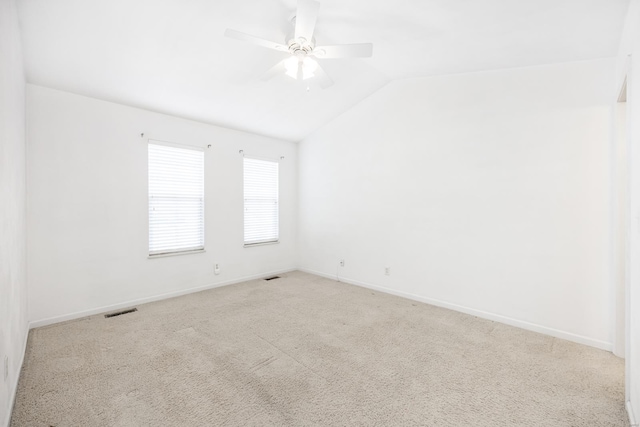 carpeted empty room with lofted ceiling, ceiling fan, visible vents, and baseboards