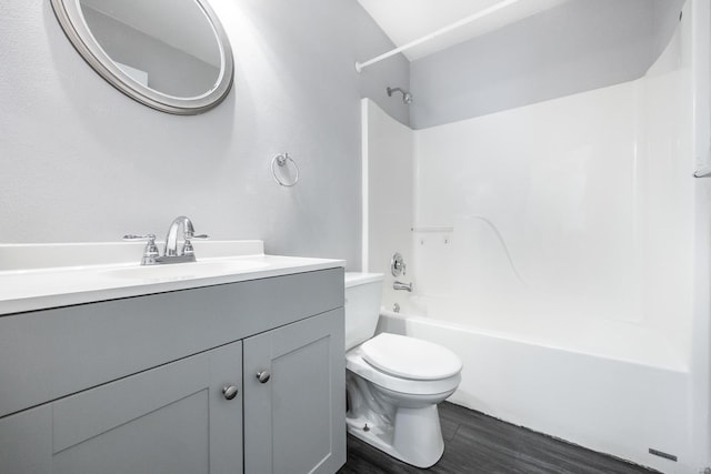 bathroom with washtub / shower combination, vanity, toilet, and wood finished floors