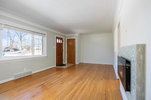 unfurnished living room with light hardwood / wood-style flooring, a fireplace, and ornamental molding