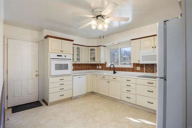 kitchen with ceiling fan, sink, backsplash, and white appliances