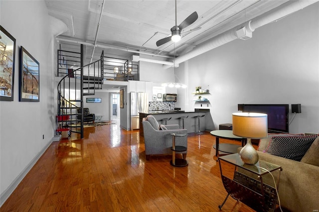 living room featuring wood-type flooring, a towering ceiling, and ceiling fan